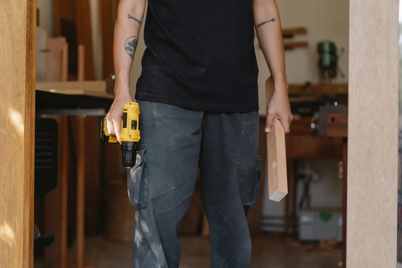 Detailaufnahme eines Handwerkers mit Akkuschrauber und Holzbauteil